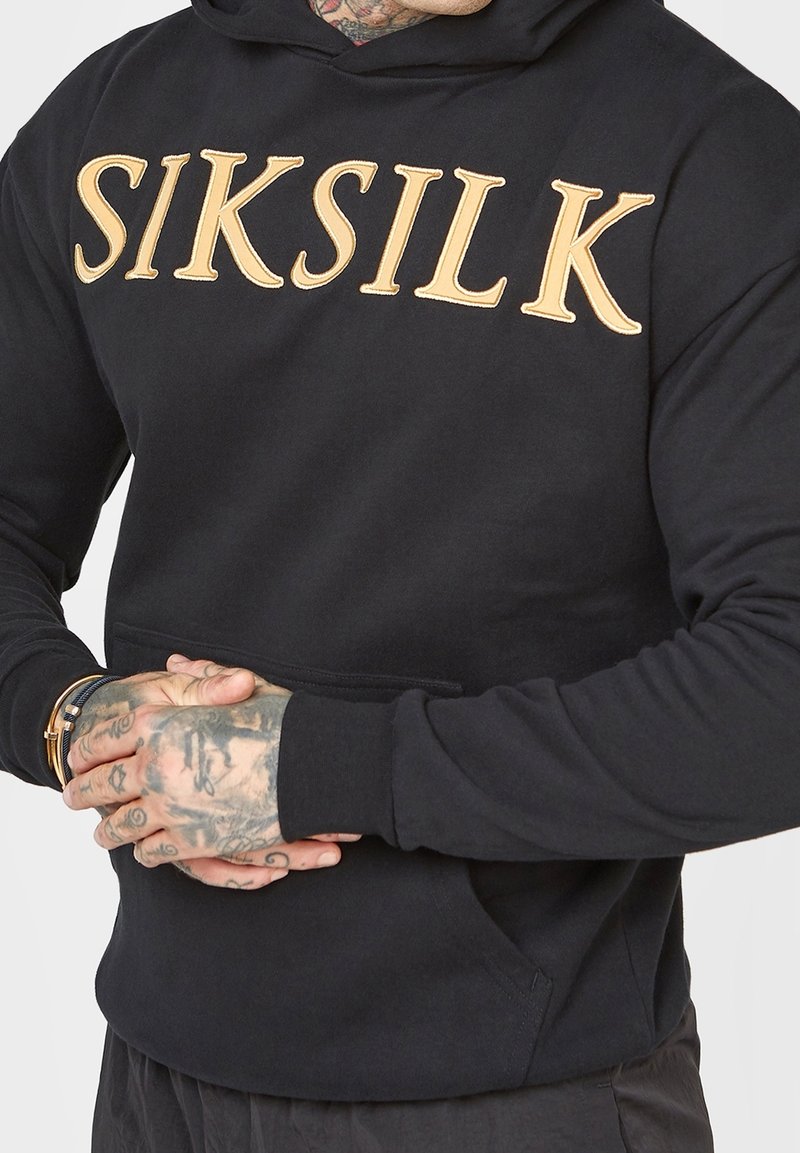 Sweat à capuche noir en coton doux, avec un grand logo doré "SIKSILK" sur la poitrine, une poche avant et une capuche avec cordon de serrage.