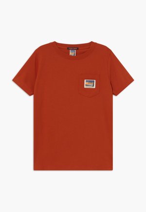 Pomarańczowy (rdzawy) krótki rękaw T-shirt z okrągłym dekoltem i kieszenią na piersi z małą prostokątną łatką z górami i tekstem.