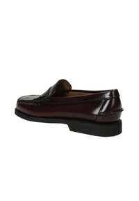 Mocassino in pelle bordeaux con tomaia cucita, punta arrotondata e suola in gomma nera bassa. Stile slip-on con dettagli minimali.
