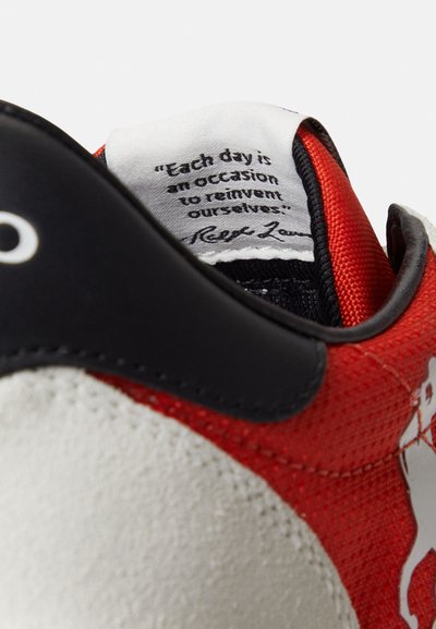 Κοντινό πλάνο από κόκκινο, λευκό και μαύρο αθλητικό παπούτσι που δείχνει την επιγραφή στη γλώσσα του εσωτερικού μέρους: «Κάθε μέρα είναι μια ευκαιρία να επανεφεύρουμε τον εαυτό μας.»