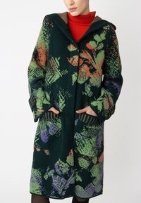 Green knitted coat featuring a floral pattern in pink, purple, and green. It has a hood, pockets, and a button closure with textured cuffs.