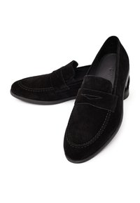 Mocassins en suède noir avec un design cousu, présentant une bande saillante sur le cou-de-pied et un petit talon empilé.