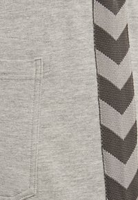 Grauer Sweatshirt-Stoff mit einem strukturierten schwarzen und grauen Chevron-Musterstreifen an der Seite. Enthält eine kleine Tasche.