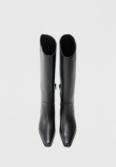 Čierne kožené čižmy po kolená s špicatou špičkou, štíhlym plášťom a detailom bočného zipsu, ktoré ukazujú hladkú textúru a minimalistický dizajn.