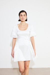 Valge satiinkleit lühikeste puhvärvidega, ruudukujulise kaelusega ja kogumise detailidega vööl, kantud tasase tausta ees.