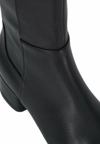 Black leather ankle boot featuring a smooth texture, rounded toe, and a low, block heel. Minimalist design with no visible hardware or accents.