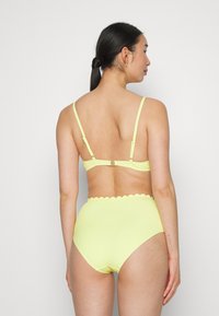 Conjunto de bikini amarelo brilhante com parte de baixo de cintura alta em formato de escalope e um bralette correspondente com alças ajustáveis e fecho de clipe.