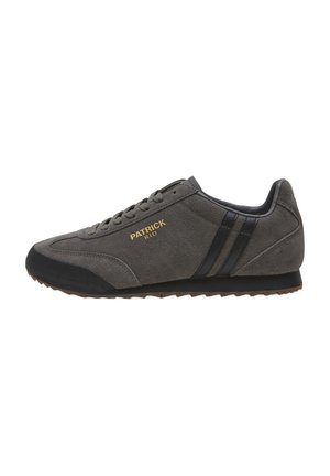 Zapatilla de ante gris con detalles en negro, que presenta una punta redondeada, suela texturizada y el logotipo dorado "PATRICK RIO" en el lateral.