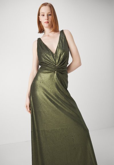 Green, floor-length dress with a deep V-neck, twisted front detail, and shimmering texture. Features two decorative buttons at the waist.