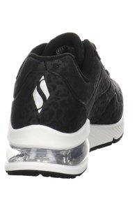 Black sneaker with a textured leopard pattern, a clear cushioned heel, and a white accent logo. Features a smooth fabric upper and sturdy sole.