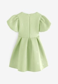 Robe vert clair avec manches courtes bouffantes, jupe plissée, fermeture éclair au dos et motif embossé subtil avec la lettre B et petits nœuds.