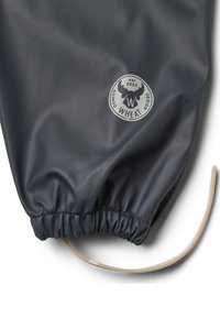 Gros plan d'un tissu imperméable foncé avec ourlet élastique et logo Danish Wheat représentant une tête d'orignal et texte "est 2002."