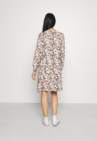 Robe fleurie avec de longues manches bouffantes, fond noir, fleurs roses et vertes, et jupe évasée, associée à des baskets blanches.