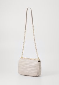 Borsa a tracolla trapuntata beige chiaro con catena dorata e texture liscia, caratterizzata da una forma rettangolare e un design minimalista.