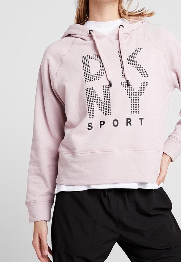 Sweat à capuche court rose clair avec cordon de serrage, orné d'un graphisme noir "DKNY SPORT". Confectionné en tissu doux avec une coupe décontractée.