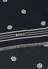 Sciarpa blu navy con motivi bianchi e bordi frangiati. Presenta un logo ripetuto e righe orizzontali con il nome del marchio "BOSS" in bianco.