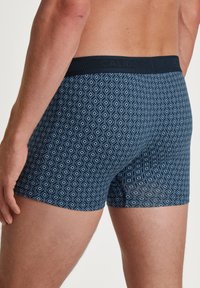 Marineblauwe boxershorts met een ruitpatroon, elastische tailleband en een gladde textuur. Heeft een getailleerd ontwerp en een lengte tot halverwege de dij.