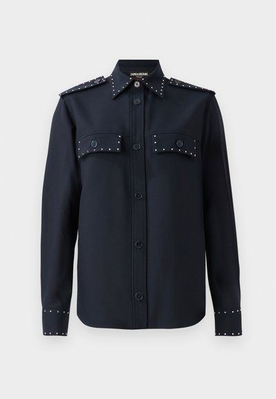 Navy shirt with long sleeves, button closure, and two front pockets. Features silver studs on pockets and cuffs, made from a smooth fabric.