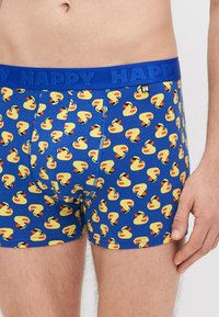 Modré boxerky s opakujúcim sa vzorom žltých gumových kačičiek s červenými zobákmi, z mäkkého materiálu a s elastickým pásom označeným nápisom "HAPPY".