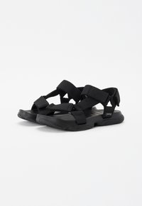 Sorte sandaler med syntetiske stropper, jevnt fordelt over foten. Lett gummisåle med teksturert såle for grep.
