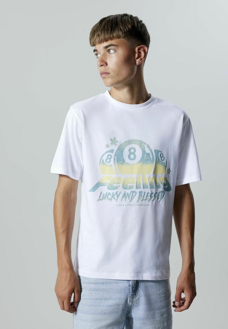 Camiseta de algodón blanca con mangas cortas y cuello redondo. El gráfico frontal presenta bolas de billar y texto en azul y amarillo. Corte casual.