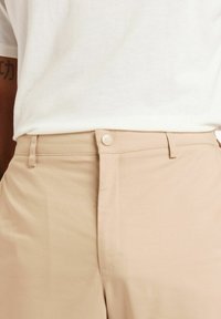 Beige, dehnbare Baumwollhose mit glatter Textur, klassischem Frontknopf und Reißverschluss, im klassischen Schnitt und maßgeschneiderter Gestaltung.