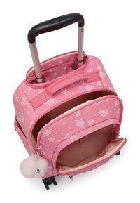 Zaino a rotelle rosa con un tessuto a motivi che presenta disegni bianchi, doppie tasche con zip, una maniglia estraibile e un portachiavi con un soffice pom-pom.