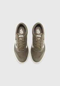 Oliven grønne sneakers med mesh overdel, rund tå, hvite detaljer på sidene og brune snorer. Teksturert detalj på tå- og hælområdene.