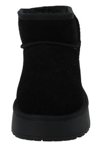 Schwarze Wildleder-Ankel-Stiefel mit einem weichen Obermaterial, abgerundetem Zehenbereich und einer strukturierten Gummisohle. Nähte entlang der Nähte verleihen Details.