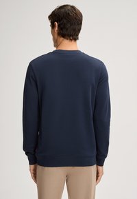 Felpa blu navy realizzata in morbido cotone, con maniche lunghe, collo a giro e polsini e orlo a coste. Dettaglio del logo discreto sul lato.