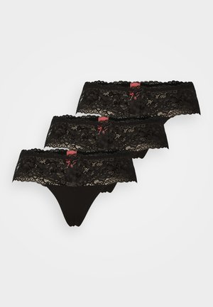 Tangas de renda preta com padrão floral na cintura, apresentando uma borda rendilhada e um pequeno laço vermelho como detalhe. Conjunto de três.