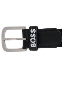 Cintura nera in pelle con fibbia in metallo argento e cinturino texturizzato. Presenta la parola ricamata "BOSS" in bianco sul passante.