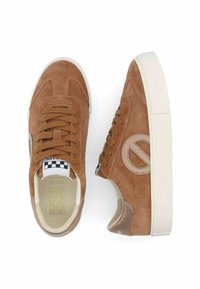Brown suede sneakers with tonal laces, white rubber sole, and a circular logo accent. Checkered insole detail is visible.
