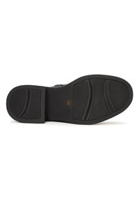 Semelle de chaussure noire avec une surface en caoutchouc texturé, dotée d'un talon plat et de rainures pour une traction optimale. Design épuré avec un détail de logo circulaire.