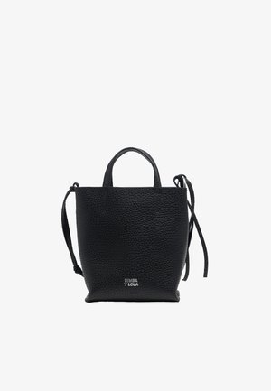 Mustassa nahkabagissa on jyhkeä pinta, kaksi lyhyttä kahvaa ja irrotettava olkahihna. Pohjassa on brändäys.