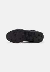 Semelle de chaussure noire avec un motif texturé reprenant le texte "HILFIGER" pour une bonne adhérence.