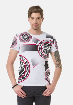 Weißes T-Shirt mit einem auffälligen grafischen Design, schwarzen und roten Kreismustern, geometrischen Formen und einer glatten Baumwolloberfläche.