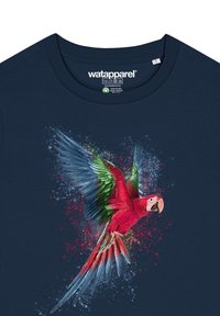 T-shirt bleu marine avec un motif coloré de perroquet aux accents rouges, verts et bleus, des plumes détaillées et un effet de projection de peinture texturé.