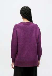 Πουλόβερ μεγάλης διάστασης από μαλακό μωβ πλεκτό ύφασμα με ριμπ μανσέτες και τελείωμα. Το σχέδιο διαθέτει στρογγυλή λαιμόκοψη και χαμηλωμένους ώμους.