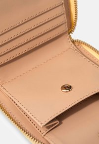 Beige Lederbrieftasche innen mit Kartenfächern, einem Druckknopfverschluss und goldfarbenen Beschlägen. Verfügt über eine glatte Textur und gestickte Details.