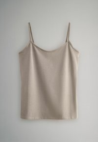 Šviesiai smėlio spalvos kamšytė su plonomis reguliuojamomis petnešėlėmis, lygiu paviršiumi, apvaliu iškirpimu ir tiesiu apačiu. Pagaminta iš minkštos medžiagos.