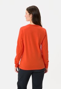 Langärmliges Shirt aus lebhaftem orangefarbenem Baumwollstoff, mit Rundhalsausschnitt und geradem Schnitt, verfügt über eine glatte Textur und ein schlichtes Design.