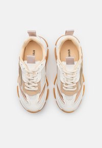 Weiße und beige Sneaker aus Mesh- und Leder-Material, mit runden Schnürsenkeln, einem goldenen Akzent und einer strukturierten Gummisohle.