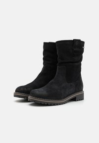 Bottines en daim noir avec un design à plis, dotées d'une languette sur le côté, d'un bout arrondi et d'une semelle en caoutchouc texturé. Des coutures accentuées définissent le style.
