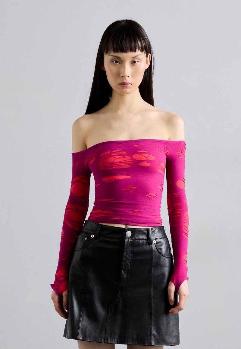 Fitted off-the-shoulder top in bright pink with cut-out patterns, paired with a black leather mini skirt featuring front pockets and silver hardware.