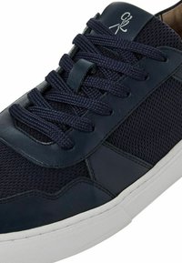 Navy blue sneaker with mesh and leather materials; features round laces, a textured design, and a white rubber sole.