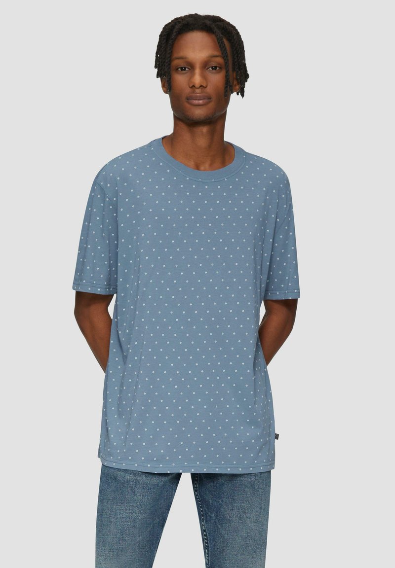 Lichtblauw T-shirt met korte mouwen en witte stippen, ronde hals, relaxed fit, gemaakt van een katoenmix. In een blauwe spijkerbroek gestoken.