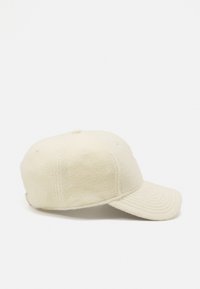 Fleece baseball cap in cream, featuring a rounded crown, adjustable strap, and pronounced visor with stitched lines. Soft texture.