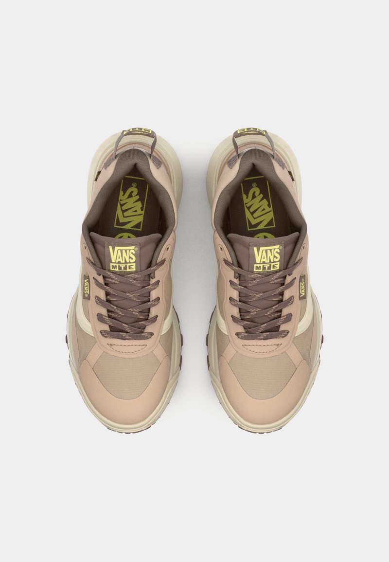 Zapatillas Vans en marrón y beige con materiales de malla y sintéticos, que presentan una punta redondeada, cierre de cordones en la parte frontal y una suela de goma texturizada.