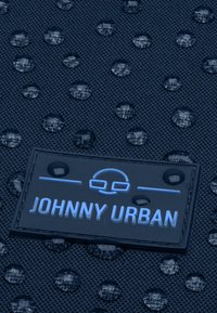 Tengerészeti vízálló anyag, texturált felülettel, vízcseppekkel és egy kék színnel gravírozott, "JOHNNY URBAN" feliratú téglalap alakú címkével.